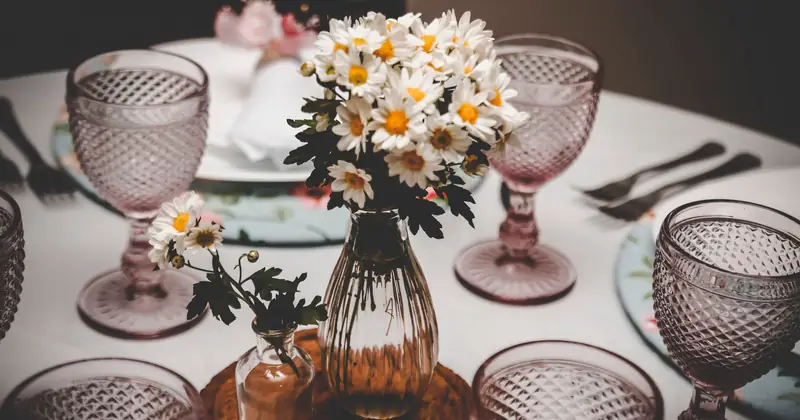 Charming table setup with vintage glasses and daisy flower arrangement, perfect for elegant dining occasions.