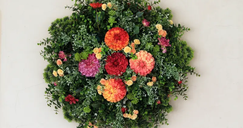 Circular floral wreath with colorful flowers against a plain background.