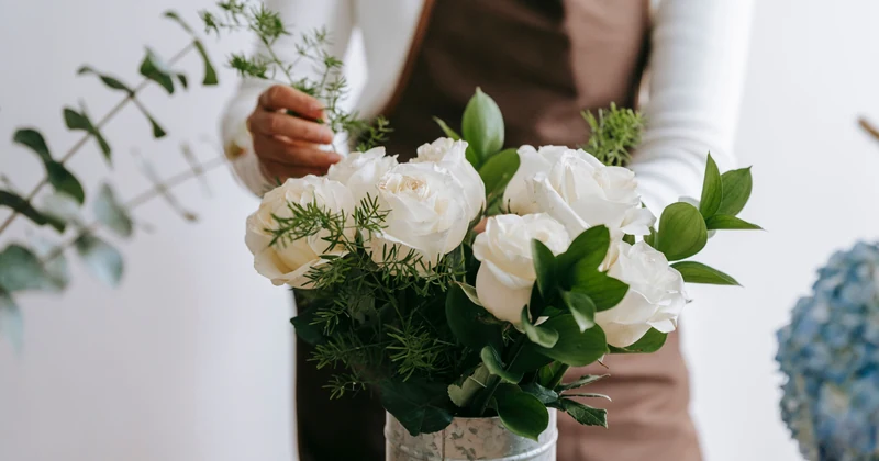 Florist arranging a bright white-rose bouquet with fresh green stems.